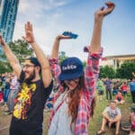 People are seen throwing their hands up and dancing at a concert at Discovery Green in Downtown Houston.